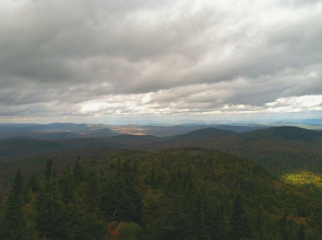 'gray clouds over rolling mountain with fall foliage'