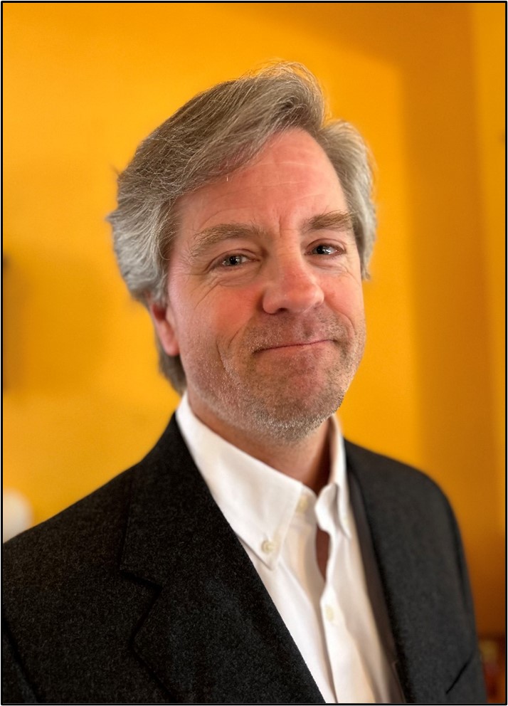 Man in black jacket in front of orange wall