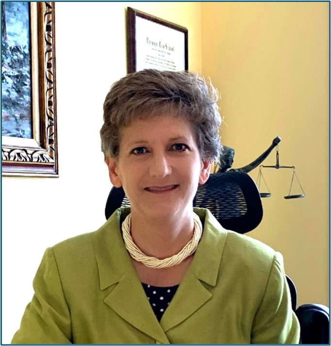 Woman in green jacket in front of yellow wall